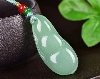 May include: A light green jade pendant in the shape of a pea pod. The pendant is suspended from a teal cord with red, green, and gold beads. The pendant is smooth and polished, with three distinct sections.