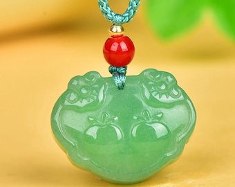 May include: A jade pendant necklace with a light green, apple-shaped charm. The charm is suspended from a teal braided cord, with a red bead and gold-colored accents. The pendant has carved details.