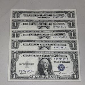 May include: Five vintage one-dollar silver certificates. Each bill features a portrait of George Washington and the text "The United States of America." The bills are in shades of gray and green.