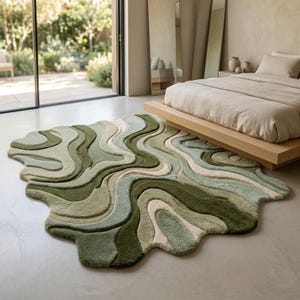 May include: An area rug with an irregular, organic shape featuring a layered, wavy pattern in various shades of green, sage, and cream. The rug has a textured, tufted surface with raised sections that create a topographical, flowing design on the floor.