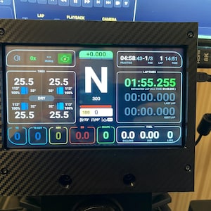May include: A digital display screen with a carbon fiber frame, showing racing data. The screen displays lap times, tire pressures, and other performance metrics. The screen is connected to a computer.