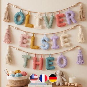 May include: Three horizontal jute rope garlands featuring crocheted, stuffed letters spelling OLIVER, ELSIE, and THEO. Each garland is finished with decorative tassels and wooden beads at both ends, displaying a variety of pastel yarn colors.