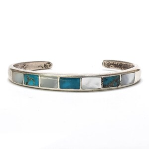 Puede incluir: Una pulsera de plata con una fila de piedras turquesa y madreperla.