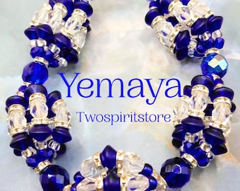 Puede incluir: Un brazalete de cuentas transparentes y azul oscuro, con detalles plateados y un cierre plateado. La palabra "Yemaya" y el texto "Twospiritstore" se muestran en azul.