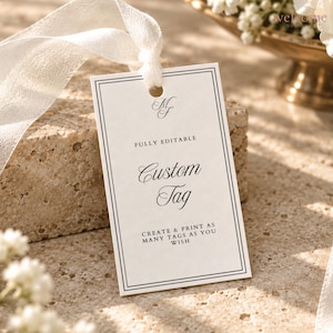 May include: A rectangular white paper tag with a double black border and a hole at the top threaded with a white ribbon. The text reads MF, FULLY EDITABLE, Custom Tag, and CREATE & PRINT AS MANY TAGS AS YOU WISH in a black serif and script font.