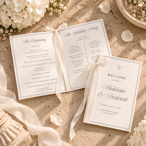 Puede incluir: Un folleto de programa de boda con cubierta color crema que presenta el texto Welcome to the wedding of Madeleine & Frederick, Saturday May 21, 20XX, Hawthorne Manor. El folleto abierto muestra The Ceremony y The Wedding Party con cinta blanca.