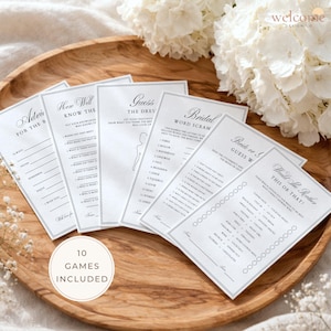 Peut inclure: Plusieurs cartes de jeux pour une fête prénuptiale, présentées sur un plateau en bois. Les jeux incluent "Conseils pour la mariée" et "Devinez la robe". Les cartes sont blanches avec du texte noir et des bordures élégantes. Des fleurs sont en arrière-plan.