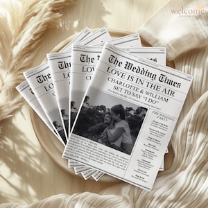 May include: A stack of wedding newspaper-style announcements. The headline reads "The Wedding Times" with the names "Charlotte & William" and the phrase "Love is in the Air." A black and white photo of the couple is featured.