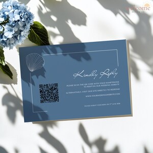 May include: A blue wedding RSVP card with a seashell graphic and the words "Kindly Reply." Includes a QR code and website address for online responses. The card is decorated with a white border and is placed next to blue flowers.
