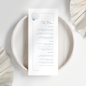 May include: A stylish menu card featuring a seashell design and the title "The Menu". The card lists starters, mains, and desserts. It rests on a white wooden plate. The top right corner displays a welcome design logo.