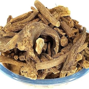May include: A clear glass bowl filled with dried, brown valerian root pieces. The roots vary in size and shape, with a rough, textured appearance. The bowl sits against a white background, highlighting the natural color and texture of the valerian.