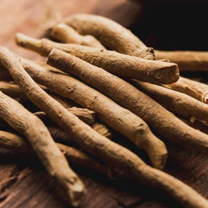 Puede incluir: Primer plano de varias ra&iacute;ces secas de ashwagandha de color marr&oacute;n claro. Las ra&iacute;ces, de diferentes longitudes y grosores, presentan una superficie rugosa y texturizada. La imagen, bien iluminada, resalta el color y la textura naturales de las ra&iacute;ces, dispuestas sobre una superficie de madera.