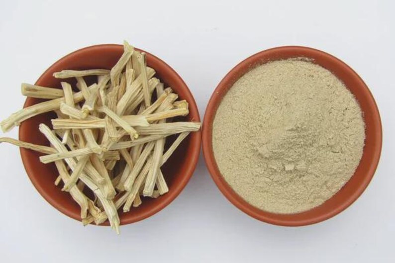 May include: Two terracotta bowls on a white surface. One bowl contains light-coloured, dried, stick-like pieces. The other bowl holds a fine, light-brown powder. The items are likely ingredients for cooking or herbal remedies.