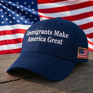 May include: A navy blue baseball cap with the slogan "Immigrants Make America Great" embroidered in white. The cap has a small American flag patch and is set against the backdrop of the American flag.