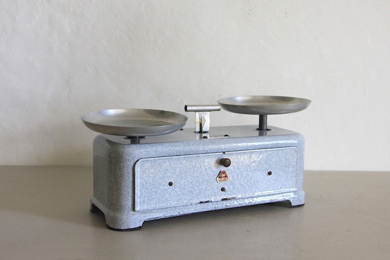 May include: A vintage blue kitchen scale with two silver metal bowls. The scale has a white label with the word "WAAGE" printed on it.