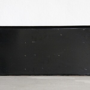 May include: A black metal rectangular sign with rounded corners. The sign is blank and has several small holes around the edges.