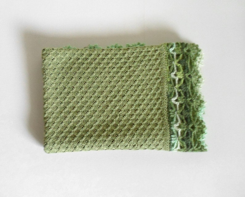 May include: A green crocheted baby blanket with a white and green crocheted border.