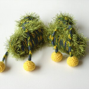 May include: A pair of green and yellow crocheted baby booties with yellow pom-poms.