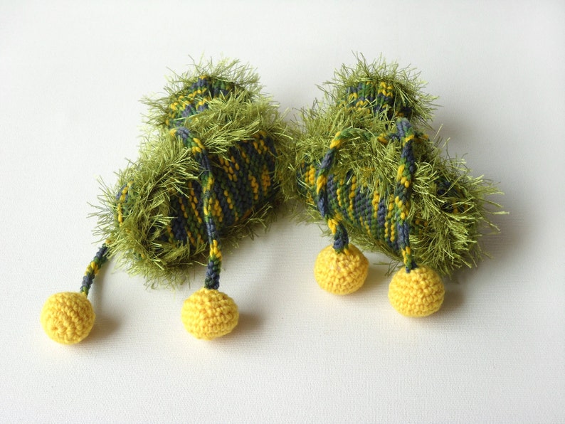 May include: A pair of green and yellow crocheted baby booties with yellow pom-poms.