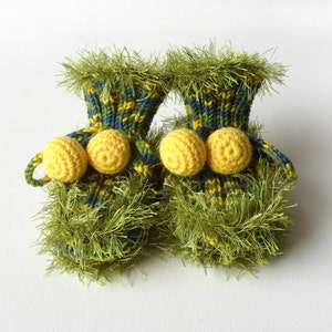 May include: A pair of green and yellow knitted baby booties with yellow pom-poms.