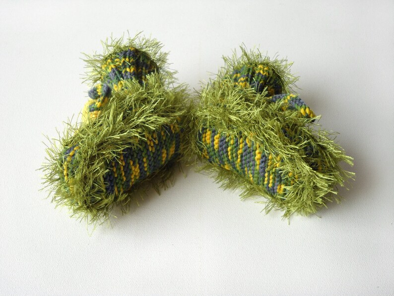 May include: A pair of green, yellow, and gray knitted baby booties with a fuzzy texture.
