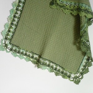 May include: A green crocheted baby blanket with a delicate lace border. The blanket is made with a soft, lightweight yarn and is perfect for cuddling.