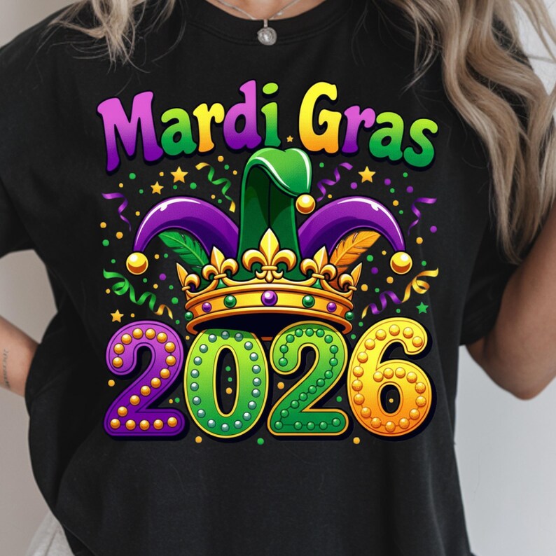 May include: Black t-shirt with a colorful Mardi Gras design. The graphic includes the words "Mardi Gras" in purple and green, a jester hat, a gold crown, and the year "2026" in green and gold.