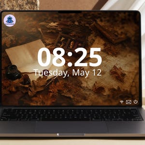 May include: A dark gray laptop displaying a digital clock reading 08:25 and the date Tuesday, May 12. The screen background features a vintage-style scene with autumn leaves, an inkwell, and parchment paper. A small circular logo is in the top left corner.