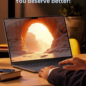 Op de afbeelding: Een laptop met een woestijnlandschap als achtergrond, met de tekst "Stop using default wallpapers! You deserve better!". De laptop staat op een houten bureau, met een pen en een boek zichtbaar. De handen van een persoon liggen op de laptop.