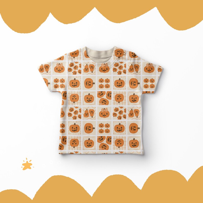 May include: A cream-coloured t-shirt with a repeating pattern of orange pumpkins, each with a different face, set within a grid. The design is ideal for Halloween, with the pumpkins in various sizes and expressions.