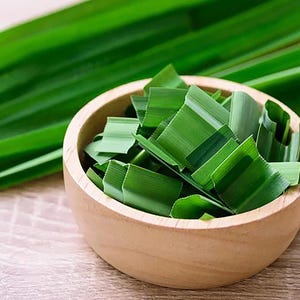 May include: A wooden bowl filled with chopped green pandan leaves, with whole pandan leaves in the background. The image also includes a green and white "100% Organic" logo.