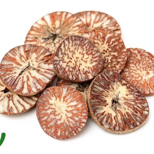 Könnte beinhalten: Ein Haufen geschnittener Betelnüsse, die ein rotbraunes und cremefarbenes Muster aufweisen. Das Bild enthält ein grünes und weißes "100% ORGANIC"-Logo unten links. Die Nüsse sind auf weißem Hintergrund angeordnet.