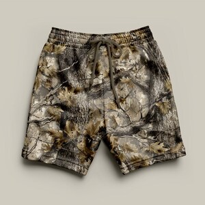 May include: Camouflage print shorts with a drawstring waist. The shorts feature a pattern of brown, tan, and grey resembling a forest scene. The shorts are made of a soft material.