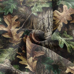 May include: Camouflage fabric with a detailed design of oak leaves and tree bark in shades of green, brown, and tan. The fabric has a realistic, textured appearance, suitable for outdoor-themed projects.
