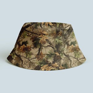 K&ouml;nnte beinhalten: Ein Camouflage-Anglerhut mit einem Waldmuster in Braun, Gr&uuml;n und Beige. Der Hut hat eine klassische, abgerundete Form mit einer leicht nach unten geneigten Krempe. Der Stoff ist ein strapazierf&auml;higes, gewebtes Material. Geeignet f&uuml;r Outdoor-Aktivit&auml;ten.