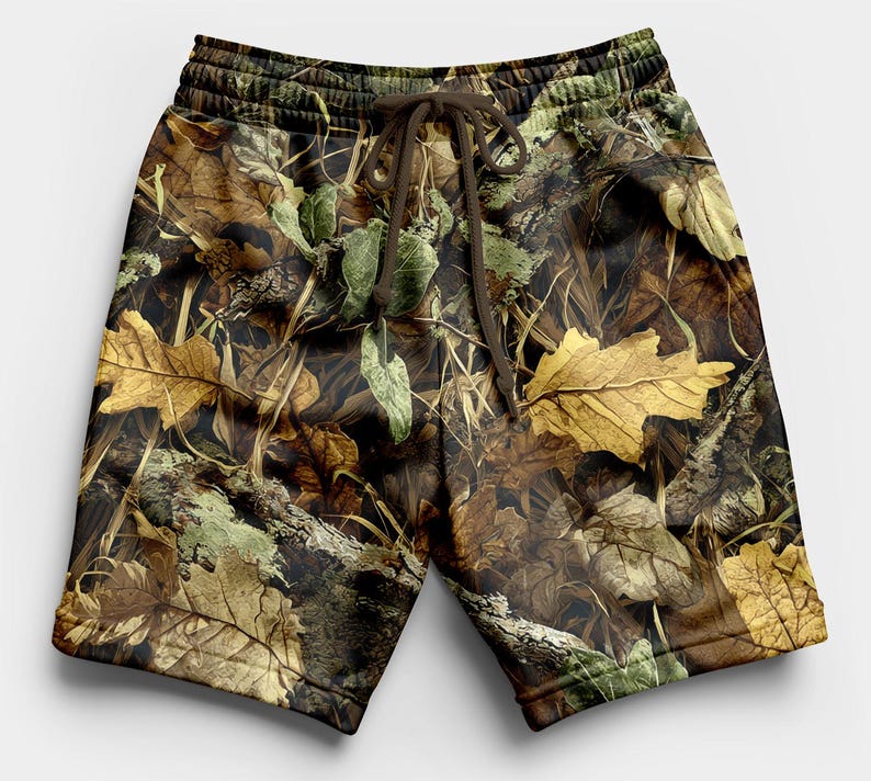 May include: Camouflage shorts with a drawstring waist. The shorts feature a pattern of brown, green, and yellow leaves and branches. The shorts are made of a soft material and are suitable for casual wear.
