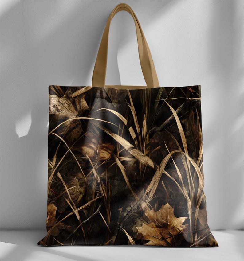 May include: A tote bag with a camouflage pattern of dried leaves and tall grass in shades of brown and tan. The bag has tan-colored handles.
