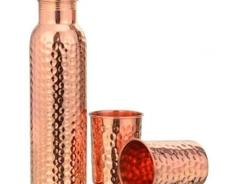 May include: A copper water bottle with a hammered texture, a matching lid, and two copper cups. The bottle and cups are displayed on a white background. The set is made of copper.