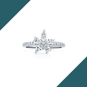 May include: A silver ring featuring a flower design made of marquise-cut diamonds. The ring's band is encrusted with small, round diamonds, creating a sparkling effect. The flower's petals are formed by the marquise-cut diamonds, with a central diamond.