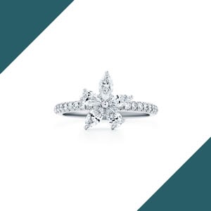 May include: A silver ring featuring a flower design made of marquise-cut diamonds. The ring's band is encrusted with small, round diamonds, creating a sparkling effect. The flower's petals are formed by the marquise-cut diamonds, with a central diamond.