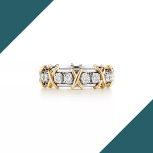 Peut inclure: Une bague en or et argent ornée d'une série de pierres précieuses rondes et transparentes. La bague présente un motif répété d'accents dorés en forme de X. La bague est posée sur un fond blanc.
