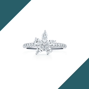 May include: A silver ring featuring a flower design made of marquise-cut diamonds. The ring's band is encrusted with small, round diamonds, creating a sparkling effect. The flower's petals are formed by the marquise-cut diamonds, with a central diamond.