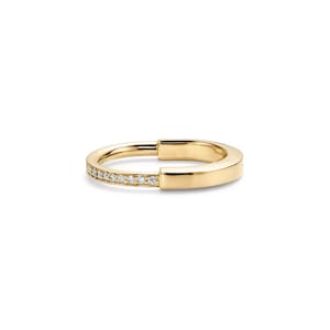 May include: A gold ring with a unique open design. One side of the ring is adorned with small, sparkling diamonds, while the other side is a smooth, polished gold band. The ring is set against a white background.