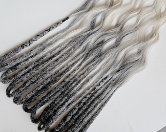 May include: A collection of gray and white dreadlocks, transitioning from dark gray at the roots to a lighter, almost white shade at the ends. The dreadlocks are arranged in a wavy pattern, with some sections tightly wound and others loose.