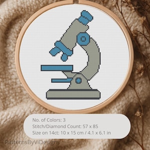 Può includere: Un ricamo a punto croce di un microscopio in un telaio di legno. Il disegno presenta un microscopio grigio e blu su sfondo bianco. Il testo sull'immagine dice "No. of Colors: 3", "Stitch/Diamond Count: 57 x 85" e "Size on 14ct: 10 x 15 cm".