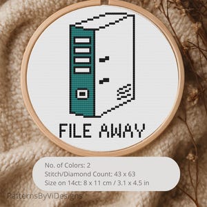 May include: A cross-stitch embroidery hoop featuring a pixelated file folder design in teal and black, with the words "FILE AWAY" below. The design is set against a white background, framed in a wooden hoop. The size is 3.1 x 4.5 inches.