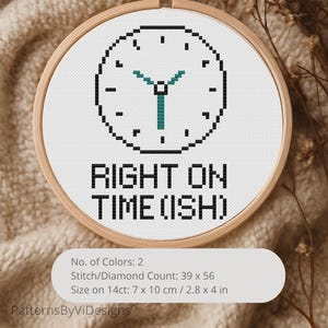 May include: A cross-stitch embroidery in a wooden hoop features a pixelated clock design with teal hands and the text "RIGHT ON TIME (ISH)". The design is on white fabric. The size is 2.8 x 4 inches.