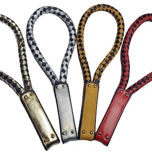 Puede incluir: Cuatro correas de muñeca de cuero trenzado en oro, plata, amarillo mostaza y rojo. Cada correa tiene una base rectangular con remaches. La parte trenzada forma un bucle. El fondo es blanco.