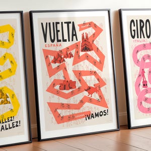 Set of three Grand Tour cycling posters—Giro, Tour, and Vuelta, focussing on Vuelta design in the centre and the Tour and Giro designs partly cropped on either side. Shown framed and leaning against a wall, the design features the race route in red on a neutral background, along with fun illustrations of cyclists, spectators and famous Spanish landmarks.