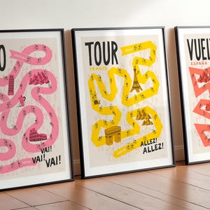Grand Tour cycling art print set, featuring Giro, Tour, and Vuelta posters in pink, yellow, and red paths on a neutral background, framed in black and displayed side by side.